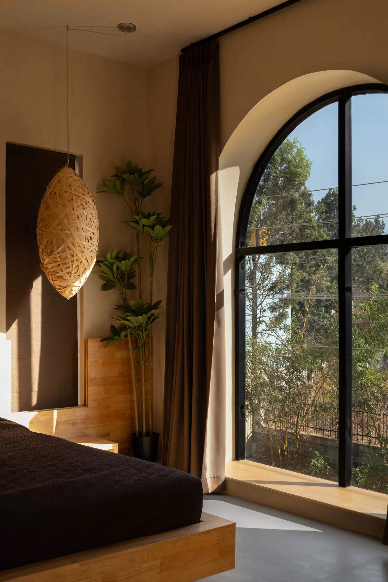 A bedroom with an arched window and woven pendant inside a Dune Villa