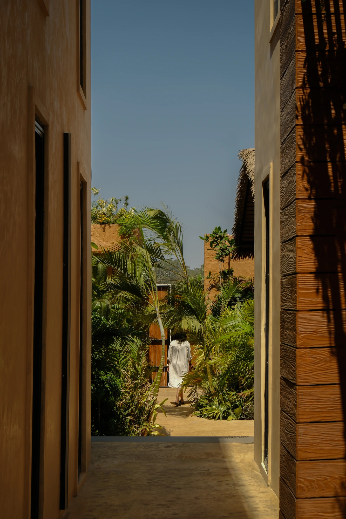 A shaded courtyard walk lined with greenery at an erth. escapes property